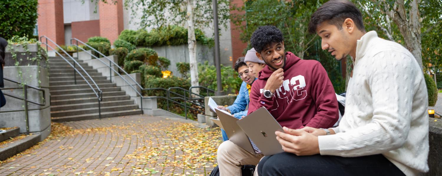 秋天，四个学生在西雅图州立大学校园的马丁广场附近互动.
